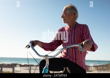 Old man with a bike at the beach Stock Photo