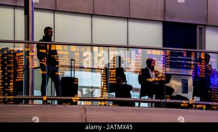 Waiting for a Train. Passengers watch the departure boards at Kings Cross Railway Station in Central London, Stock Photo