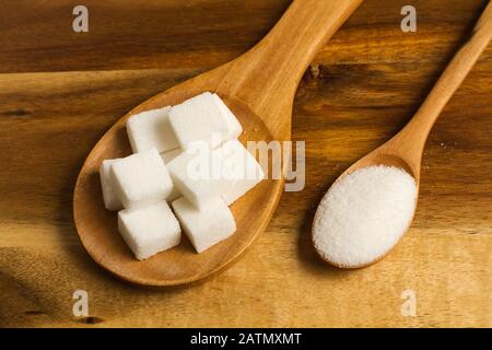 Sugar cubes on a wooden spoon and white sugar on a wooden spoon Stock Photo