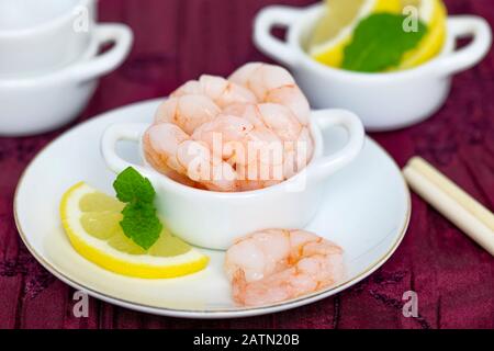 close up  of king prawns peeled and cooked whole with lemon and mint on a dish,   blurred background for copy space Stock Photo