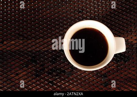 Coffee in white mug on black grid. Horizontal photo with copy space to the left. Stock Photo