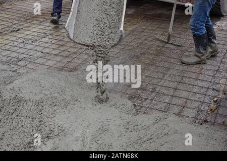 workers pouring wet concrete using concrete bucket. Industrial construction. Stock Photo