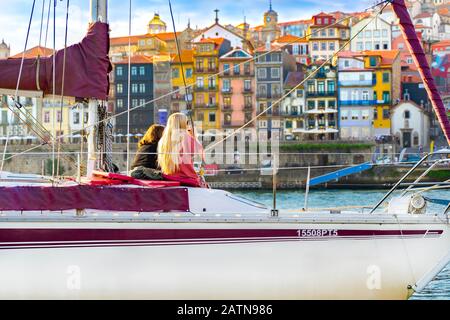 women on a private yacht drinking wine and enjoying sunset view in Porto, Portugal. back view. Panorama old city Porto at river Duoro. Oporto panorama Stock Photo