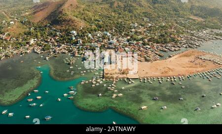 sea port, pier, cityscape Coron town with boats on Busuanga island, Philippines, Palawan. Coron city with slums and poor district. Seascape with mountains. Stock Photo