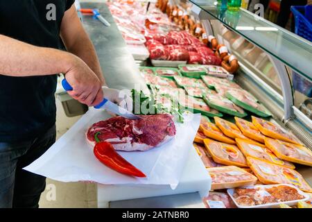 Butcher is working in a meat section of a market and chopping meat. Food and culinary concept Stock Photo