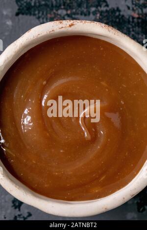 Homemade salted caramel sauce in ceramic bowl. Close up, food background Stock Photo