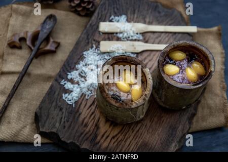 Sticky Rice Cooked with Coconut milk (Khao lam) or Glutinous rice roasted in bamboo joints on wooden, Thai dessert concept, Oblique view from the top. Stock Photo