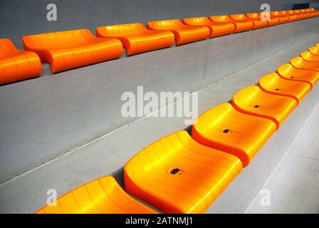 Rows of empty orange plastic seats at stadium Stock Photo