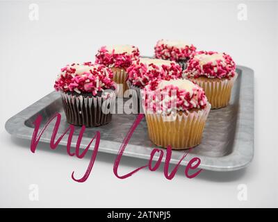 Rustic tray of chocolate and vanilla cupcakes decorated for Valentine’s Day with white frosting and red, white and pink sprinkles, on a white backgrou Stock Photo