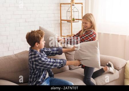 Boy And Girl Having Fun Fighting With Pillows At Home Stock Photo