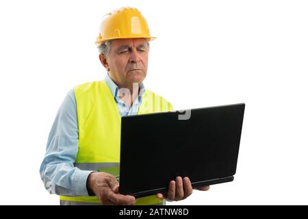 Serious old architect man wearing vest and hardhat looking at laptop isolated on white studio background Stock Photo