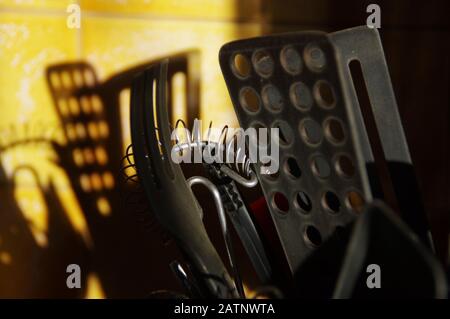 Kitchen tools that cast a shadow on the ceramic wall. Morning in the kitchen. Stock Photo