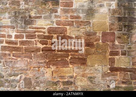 Very old, brown, partly heavily weathered stone wall Stock Photo