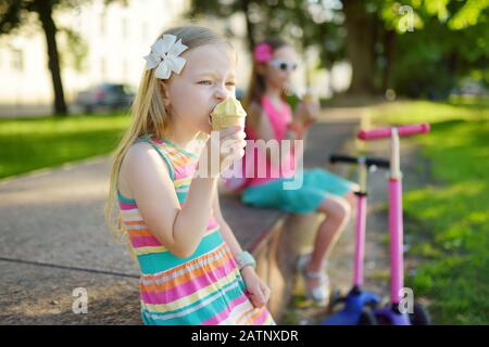 Cute little children eating tasty fresh ice cream in sunny summer park. Kids eating sweets. Unhealthy food for kids. Stock Photo