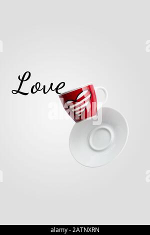 Love writing spilled out of valentine's cup of coffee with heart balancing in the air or falling isolated on white background, levitation creative des Stock Photo