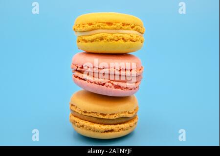 Stack of sweet french macaroons with vintage pastel colored tone on blue background . Stock Photo