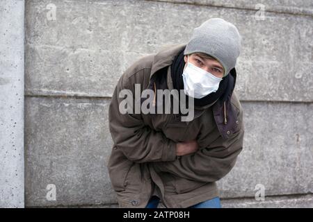 the person in the medical face mask became ill. abdominal pain with viral disease. Stock Photo