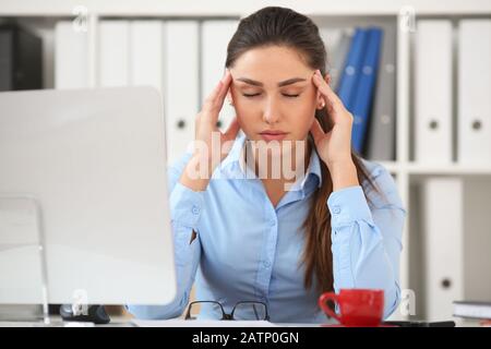 Business woman experiencing stress in the workplace, holding her hand behind her head Stock Photo