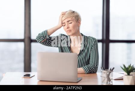 Lady Touching Head Suffering From Pain Sitting In Modern Office Stock Photo