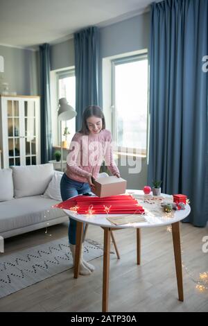 Dark-haired girl in a pink shirt holding a present box Stock Photo