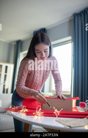 Dark-haired girl in a pink shirt looking involved Stock Photo