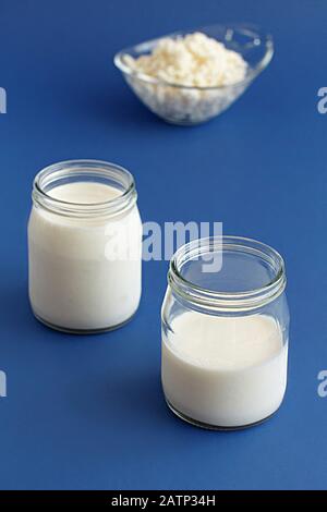 Fermented drink kefir in small bottles and kefir grains on a blue background close up Stock Photo