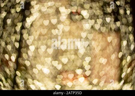 Valentines background. Abstract golden heart bokeh background. Defocused blurred heart shaped lights. Stock Photo