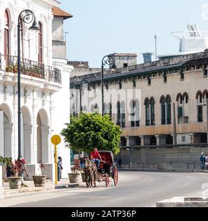 Havana, Cuba - 25 July 2018: A man sits in his horse and buggy hoping to give a ride to tourist on the streets of Havana Cuba with the top of a cruise Stock Photo