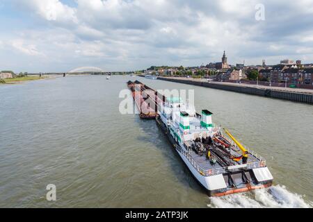 Cargo riverboat passing the Dutch city Nijmegen on the river Waal Stock Photo