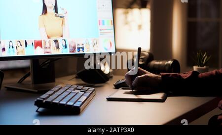 Creative photographer retouching photos at night. Retouching using digitizer. Stock Photo