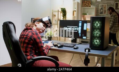 Gamer girl losing video game tournament while playing with VR headset late at night in her room Stock Photo