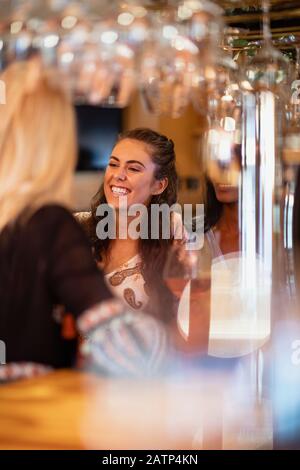 Female friends having drinks and laughing at a bar. Stock Photo