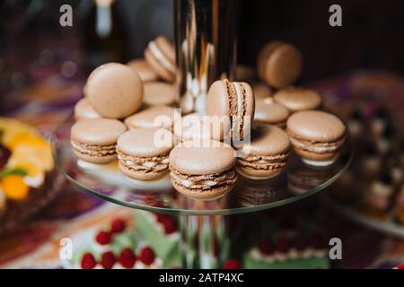 Chocolate macaroons lie on a glass slide for desserts. Candy bar. Stock Photo