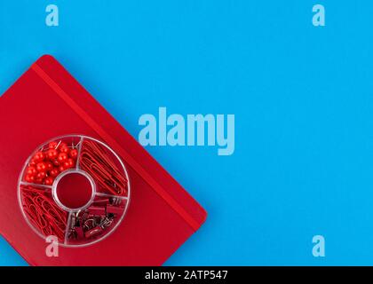 Red Business notebook and stationery on blue table. Back to school or workplace abstract background. Minimal composition. Stock Photo