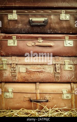 Retro styled image of old suitcases on hay Stock Photo