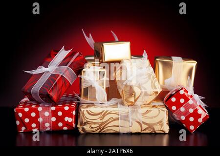 Pile of colorful gift boxes with ribbons on red background. Concept of christmas or special day gifts. Close up view. Stock Photo
