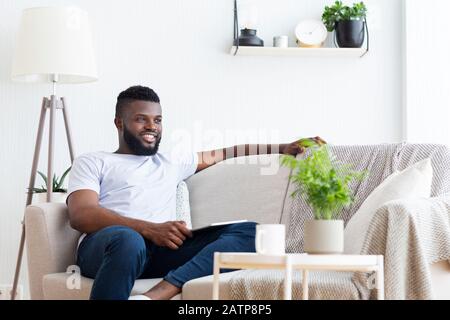 Cheerful afro man relaxing at home with digital tablet Stock Photo