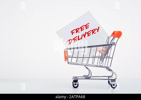 Shopping cart with a note paper writing free delivery on it on white background with copy space. Stock Photo