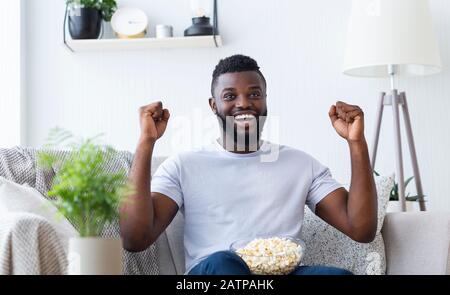 Excited african american man enjoying sports on tv at home Stock Photo