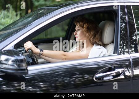 Confident beautiful woman with wristwatch driving car. Stock Photo