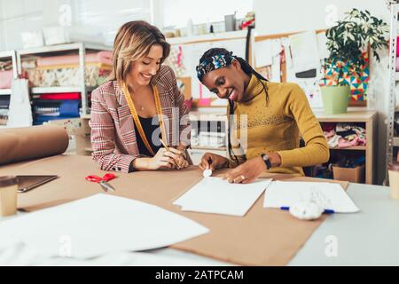 Two young entrepreneur women, or fashion designers working in atelier Stock Photo