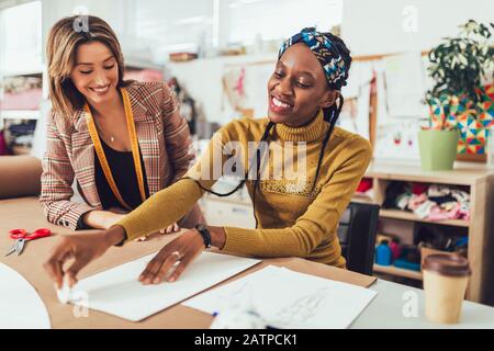 Two young entrepreneur women, or fashion designers working in atelier Stock Photo