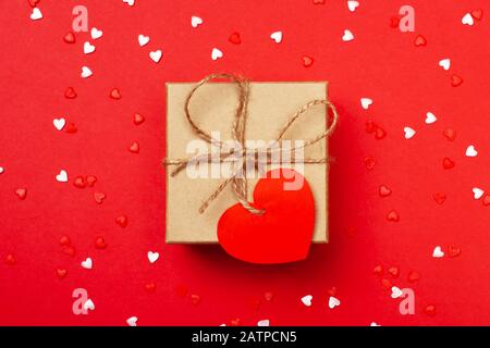 A gift with cute heart on the red background. Surprise your loved one. The concept of the St. Valentine's day, birthday and other holidays. Zero waste. Flat lay Stock Photo