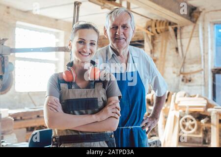 Senior master carpenter with his granddaughter in the wood workshop Stock Photo