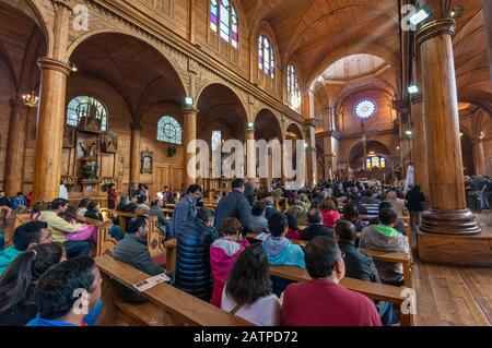 Churchgoers at Easter Mass in Iglesia San Francisco, wooden church in Castro, Isla Grande de Chiloe, Los Lagos Region, Patagonia, Chile Stock Photo