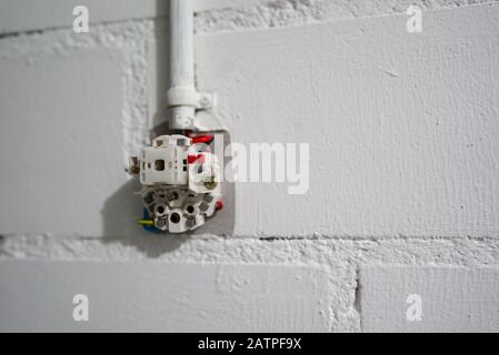 A selective focus close up of partially installed wall socket for electricity in a bright cellar room Stock Photo