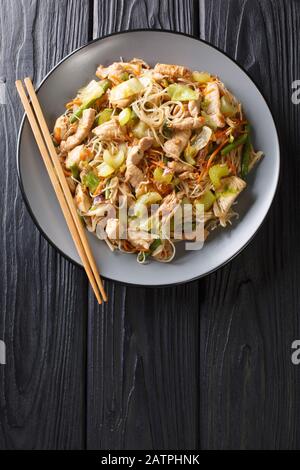 Delicious Filipino food Pancit Bihon rice noodles with vegetables and meat close-up in a plate on the table. Vertical top view from above Stock Photo