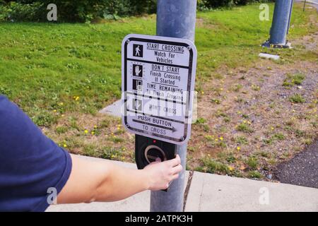 Pedestrian presses the button. A pedestrian light switch with voice guidance and comprehensive operating instructions. Stock Photo