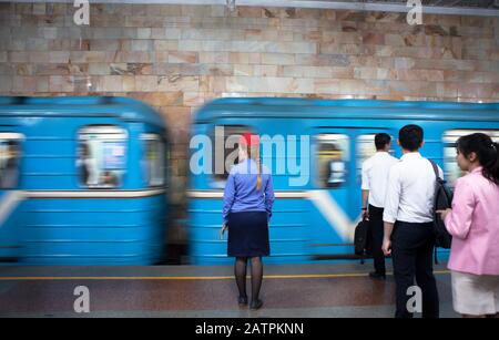 Conductor in uniform and passengers waiting at the passing train, Tashkent metro station, Tashkent province, Uzbekistan Stock Photo