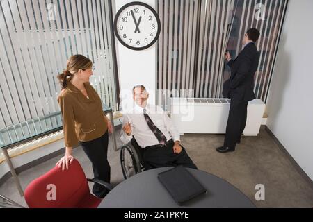 High angle view of two business executives smiling with another businessman looking through window behind them Stock Photo